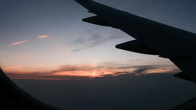 Airplane wing over sunset horizon