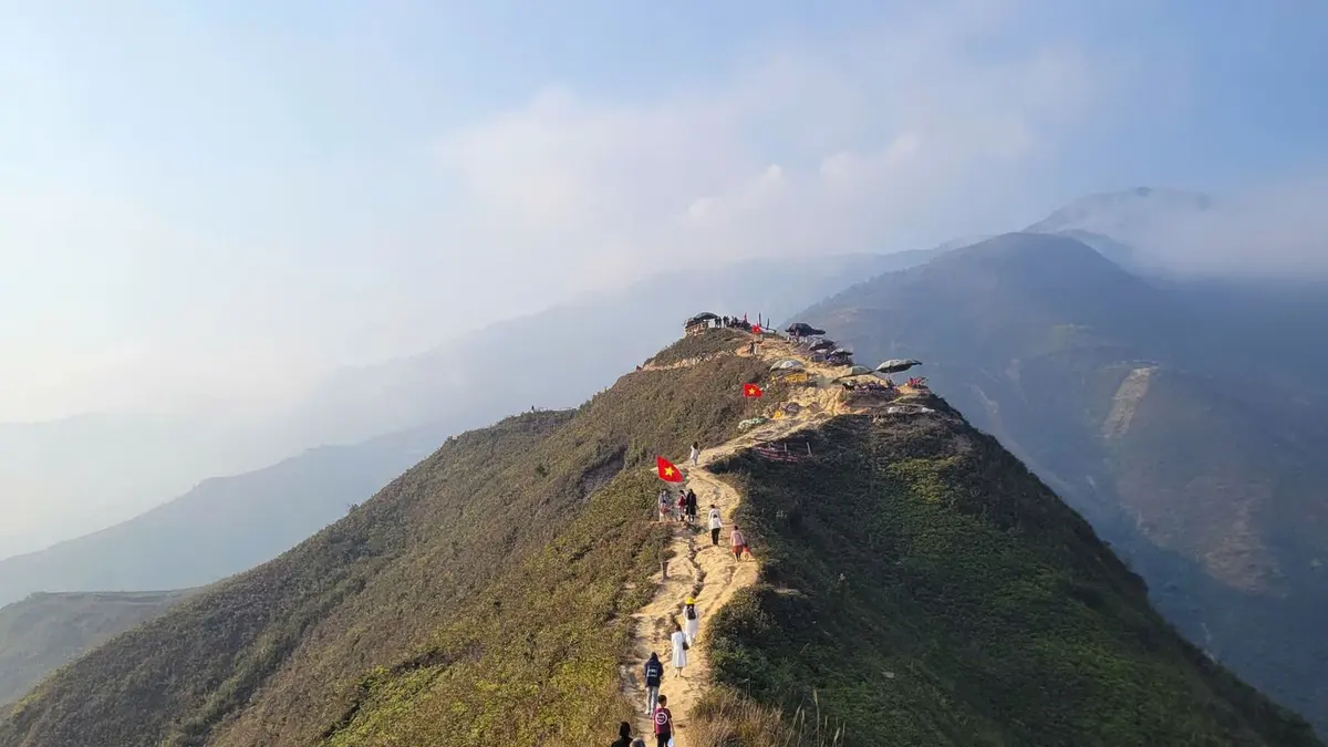 Hikers ascending a mountain ridge at sunrise
